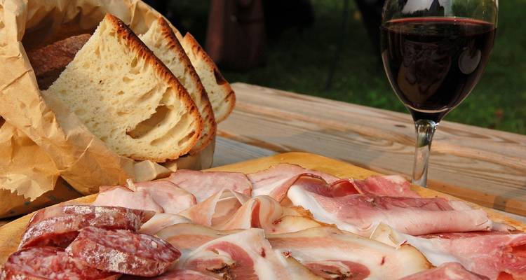 Eine Platte mit verschiedenen Aufschnitten, Brot und Wein.