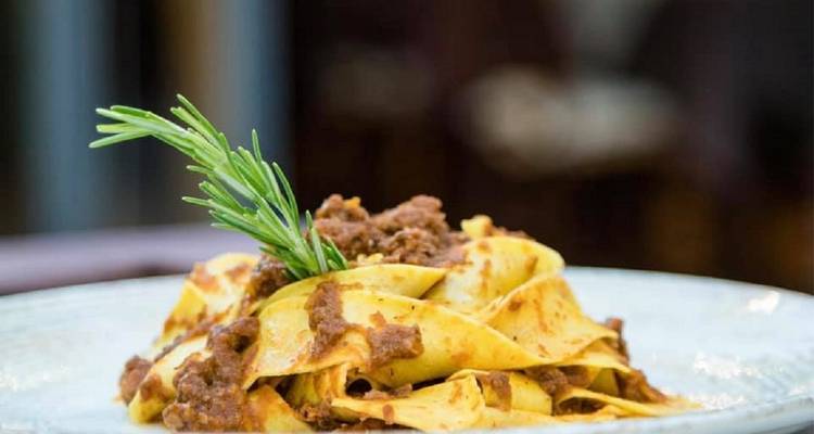 Pasta dish garnished with rosemary on a plate.
