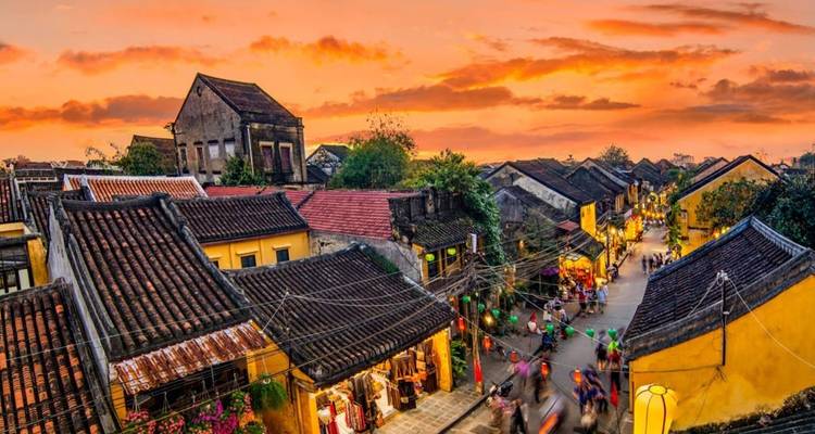 Belebte Straße in einer traditionellen Stadt bei Sonnenuntergang mit lebendigen Gebäuden und Menschen.