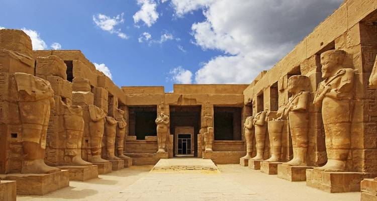 Cour du temple de Karnak avec des statues grandioses et un ciel bleu.