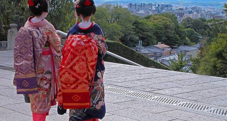 Twee vrouwen in traditionele kleding kijken uit over een stadslandschap.