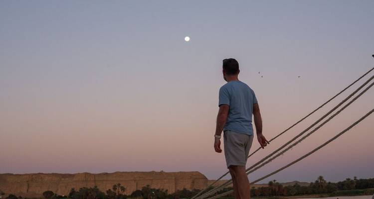 Mann steht auf einem Boot und blickt auf den Mondaufgang.