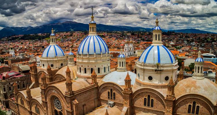 Die blaugedeckelten Kuppeln der Kathedrale von Cuenca erheben sich unter dramatischen Wolken über die Stadtsilhouette.