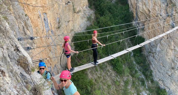 Gruppe von Menschen, die eine Hängebrücke an einer Klippe überqueren.