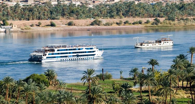 Des bateaux de croisière naviguant sur le Nil entourés de palmiers.