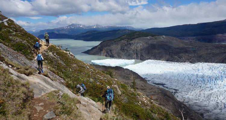 Des routards en randonnée sur un sentier élevé surplombant le glacier Grey et le lac turquoise dans les Torres del Paine.