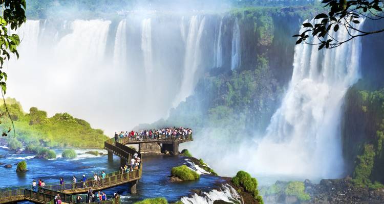 Crowds stand on viewing platforms surrounded by the powerful cascades and mist of Iguazu Falls.
