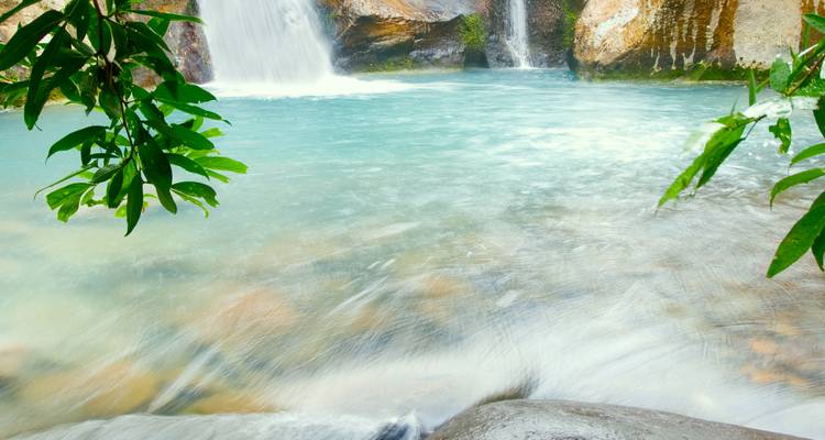Helder turquoise zwembad aan de voet van een kleine junglewaterval omgeven door weelderig groen in Costa Rica