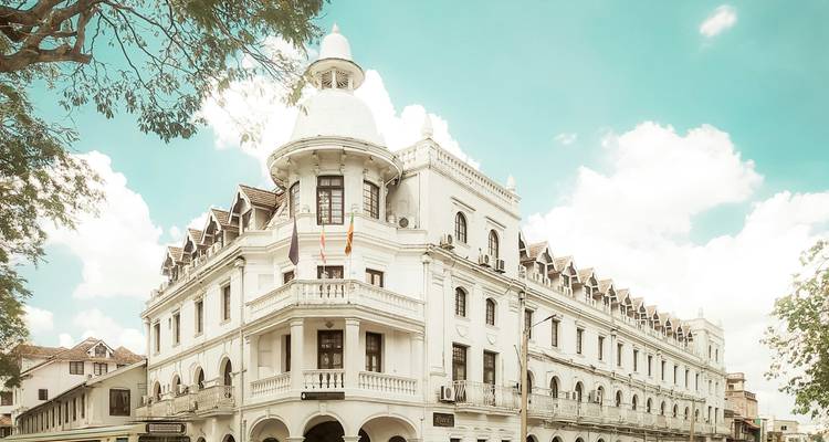 Elegante edificio de hotel blanco de la era colonial bajo un cielo tropical brillante en Kandy.
