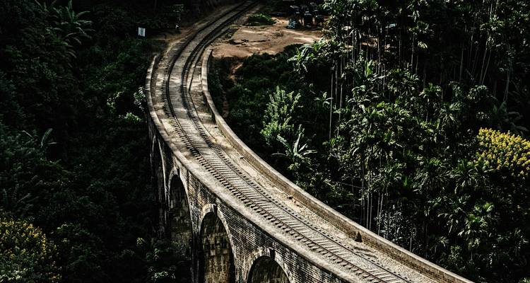 Repite imagen: vista aérea del Puente de Nueve Arcos curvándose a través de exuberante bosque.