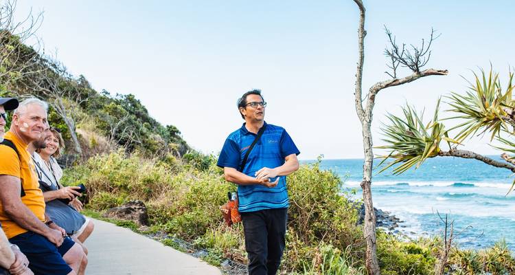 Grupo de personas escuchando a un guía junto al océano.
