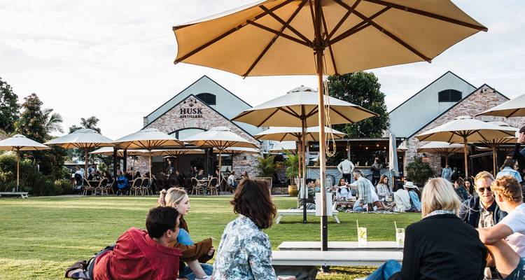 Escena animada al aire libre con personas disfrutando de su tiempo libre bajo sombrillas.