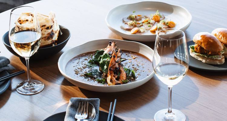 Varios platos gourmet y copas de vino sobre una mesa de madera.