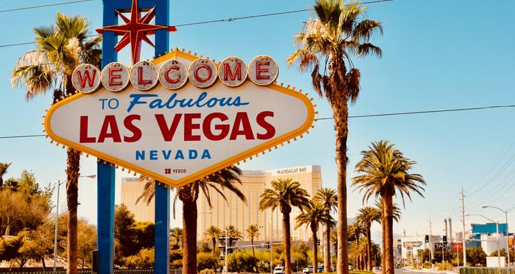Berühmtes Las Vegas Schild mit Palmen unter einem hellen Himmel.