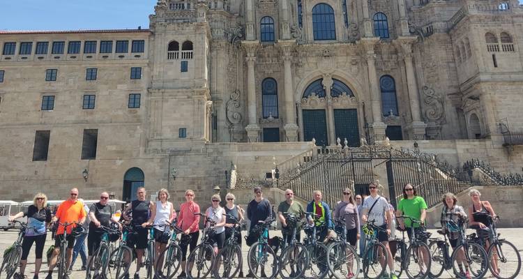 Group of cyclists posing with their bikes in front of Santiago de Compostela’s ornate stone cathedral