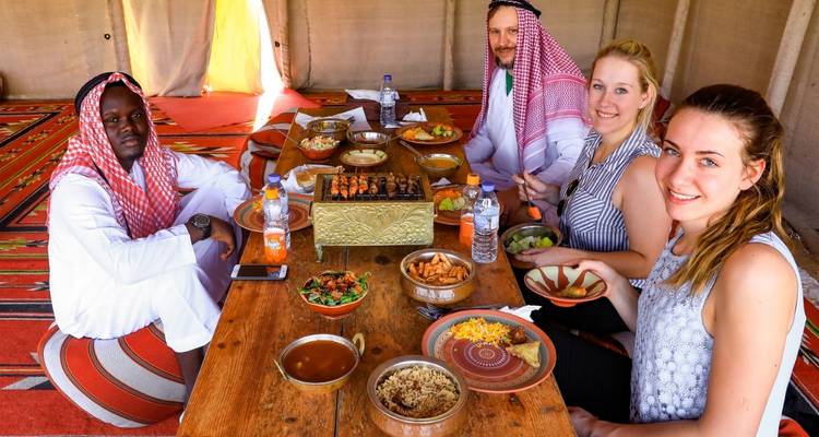 Gruppe von Menschen, die sich in einem Zelt an einer traditionellen Mahlzeit erfreuen.