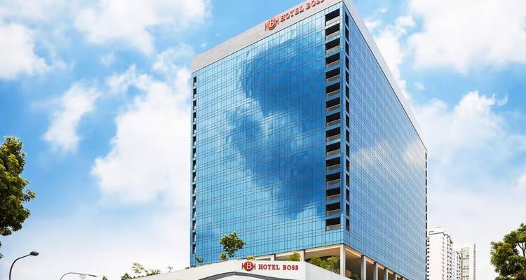 Glassy facade of Hotel Boss rising against bright blue sky.