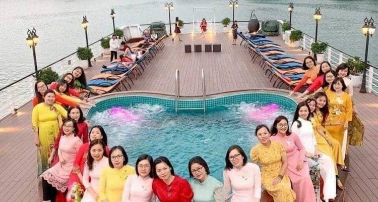 Groep mensen bij een zwembad op een cruisedek met uitzicht op de kust.