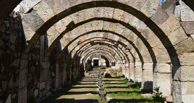 Stenen bogen die een tunnel vormen met schaduwen en licht.