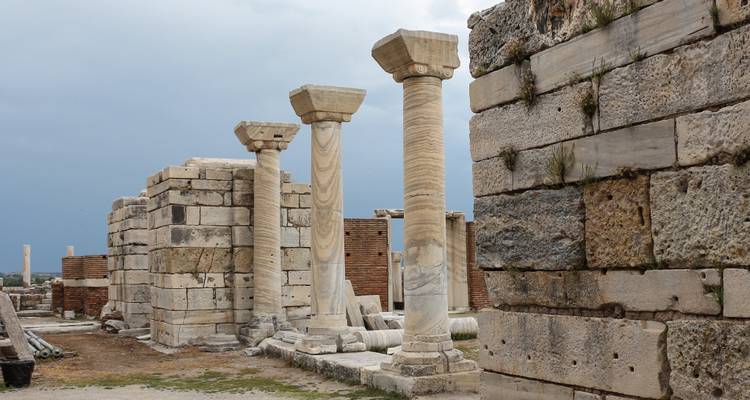 Oude stenen zuilen en structuren met bewolkte luchten.