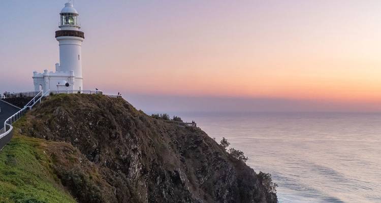 Un faro en un acantilado durante la puesta de sol, con vista al océano.