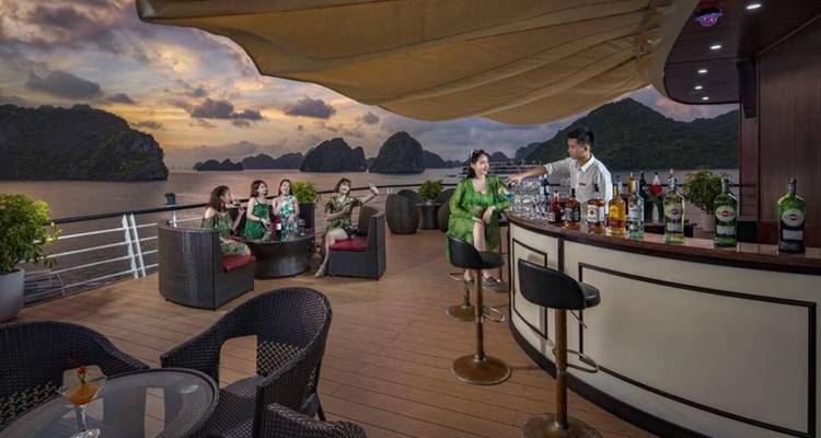 Groep mensen die genieten van drankjes op een scheepsdek bij zonsondergang.