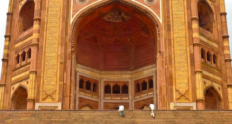 Massives verziertes Tor mit zwei Personen, die die Treppe hinaufsteigen.