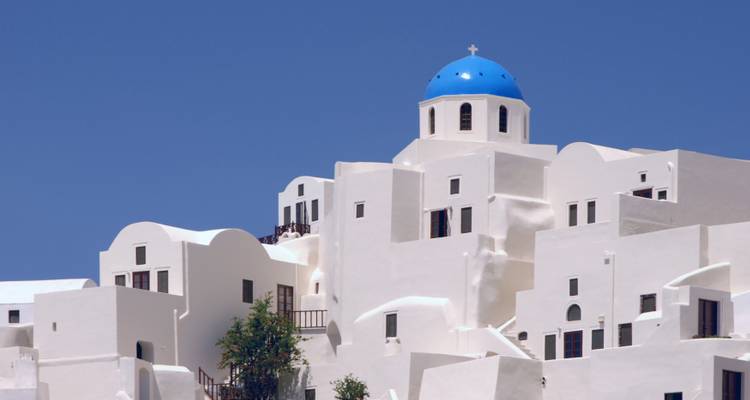 Edificios blancos con cúpulas azules contra un cielo azul claro en Santorini.