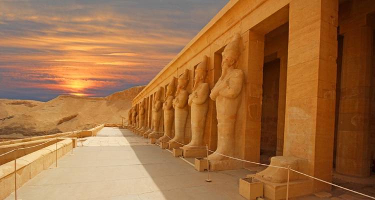 Row of statues at an ancient Egyptian temple during sunset