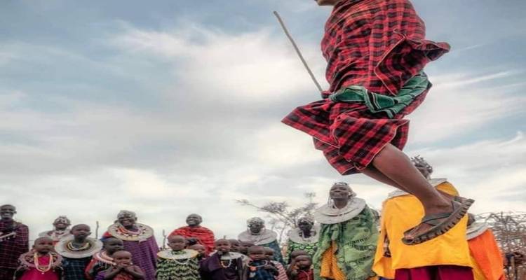 Eine Gruppe von Menschen, einige in traditioneller Kleidung, beobachten eine Person beim Springen.