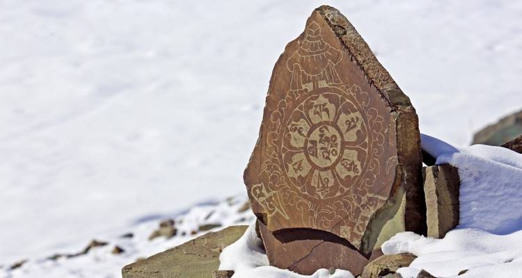 Engraved stone on snow-covered ground.