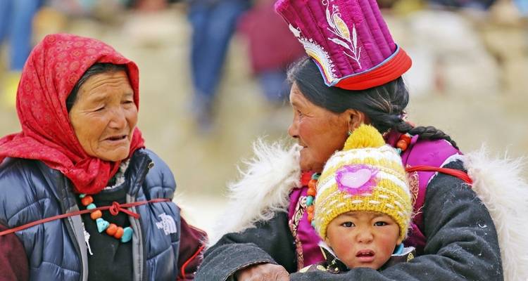 Two women and a child in traditional attire, having a conversation.