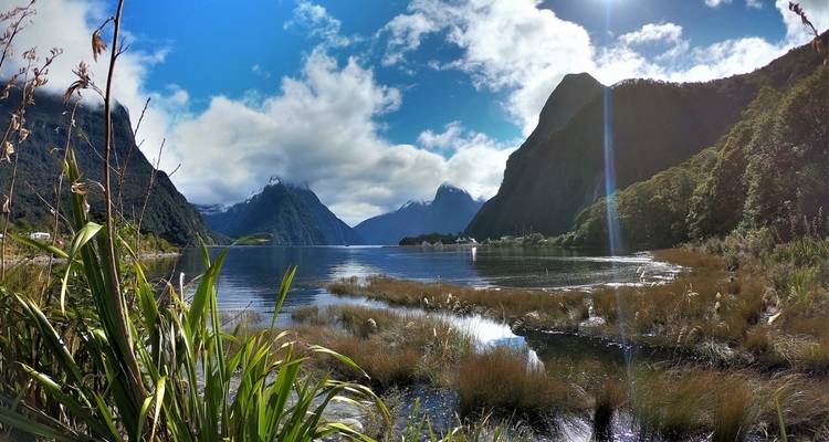 A scenic view of a lake surrounded by mountains and clouds.