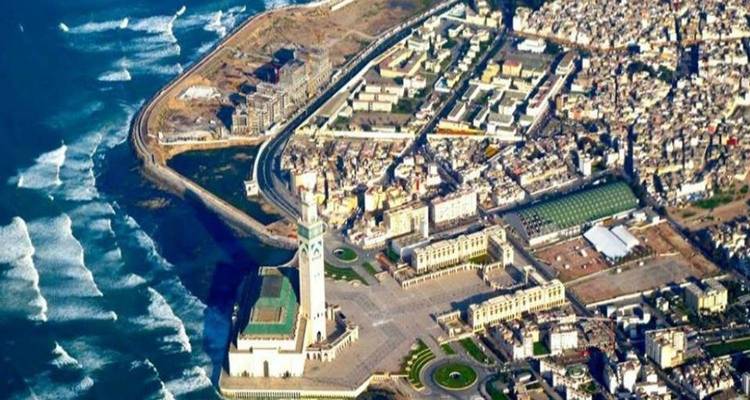 Aerial view of a coastal city with a prominent square and mosque.
