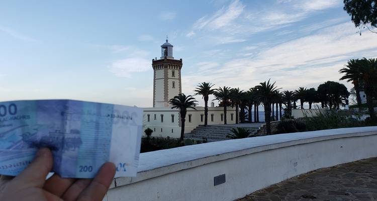 Lighthouse with palm trees and currency note in foreground.