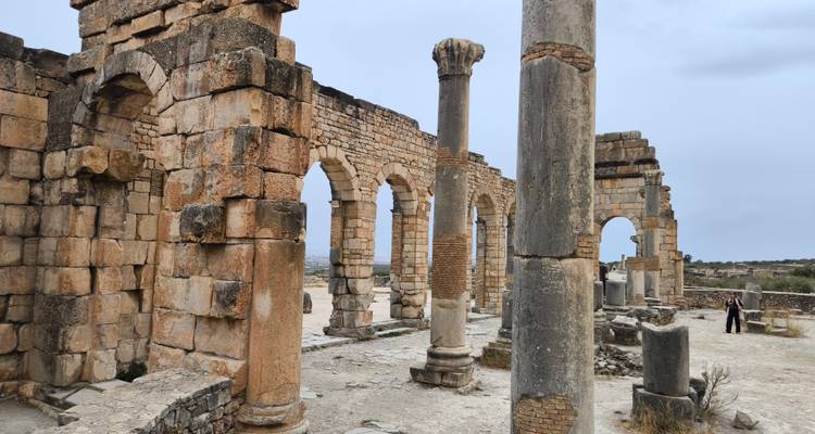 Römische Ruinen mit Steinbögen und Säulen.