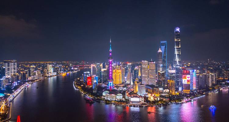 Paysage urbain nocturne avec des lumières vives se reflétant sur un plan d'eau.