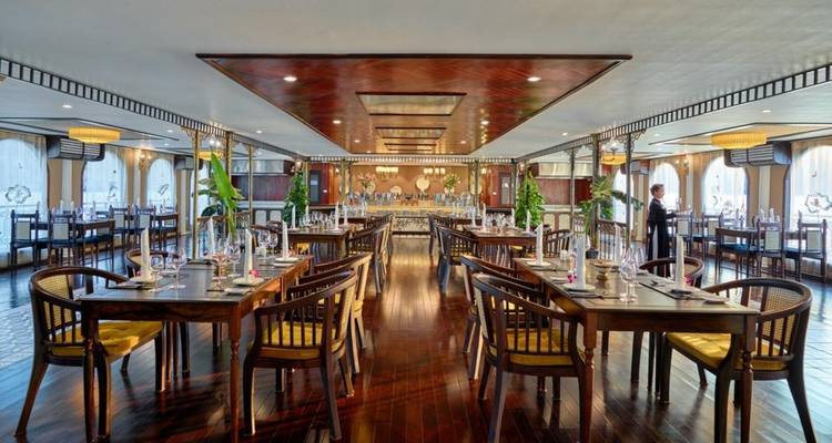 Eetgedeelte op een cruiseschip met meerdere tafels en decoraties.