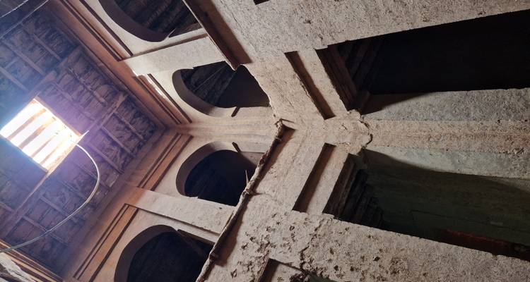 Vue architecturale intérieure avec poutres et structure en pierre.