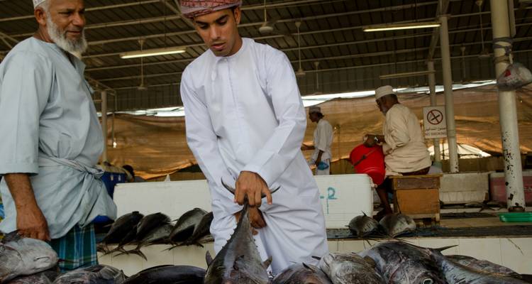 Mannen op een vismarkt die met elkaar omgaan.
