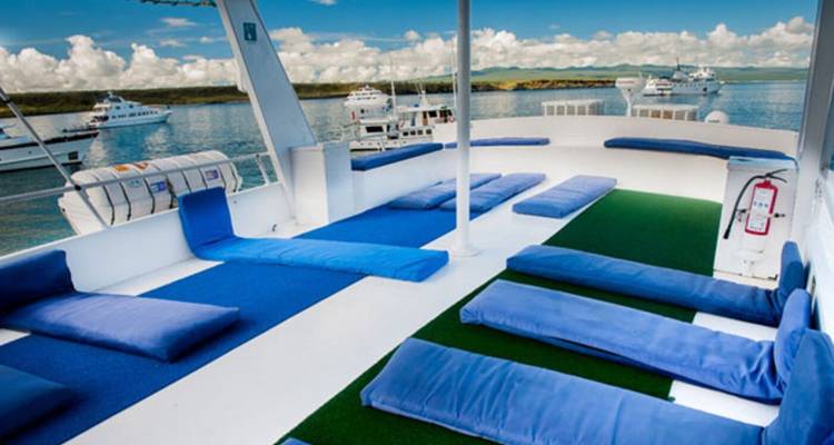 Deck area with cushions and boats in the background.