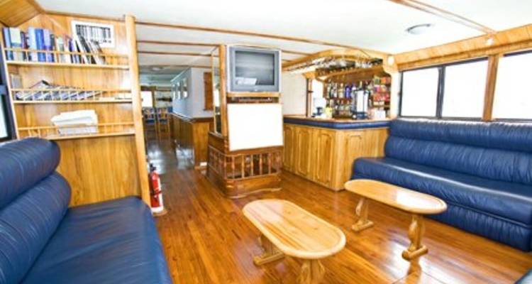 Boat lounge area with wooden interiors and a TV.