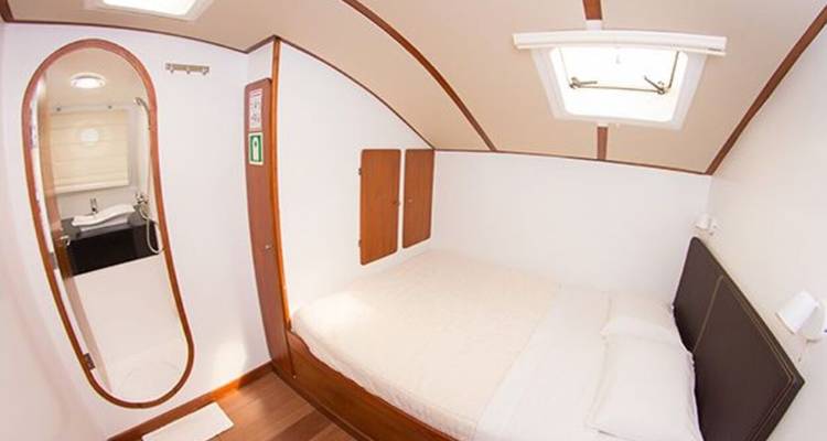 Cabaña luminosa con una cama doble y baño privado visible a través de una puerta ovalada.