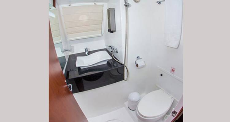 Baño marino compacto con lavamanos, espejo e inodoro dentro del yate.