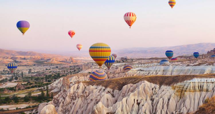 Hot air balloons floating over a rocky landscape.