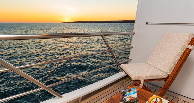 Terras met zitplaatsen, uitzicht op de oceaan bij zonsondergang.