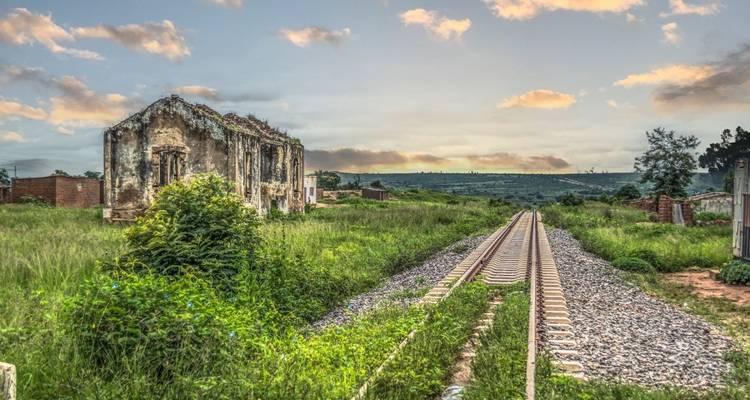 An abandoned building next to a railway track in a rural setting.