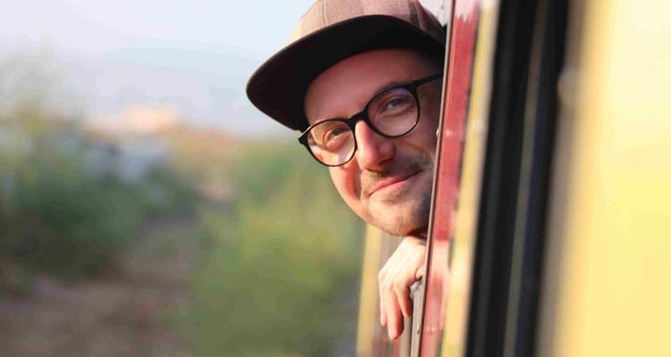Un homme regardant par la fenêtre d'un train, souriant.