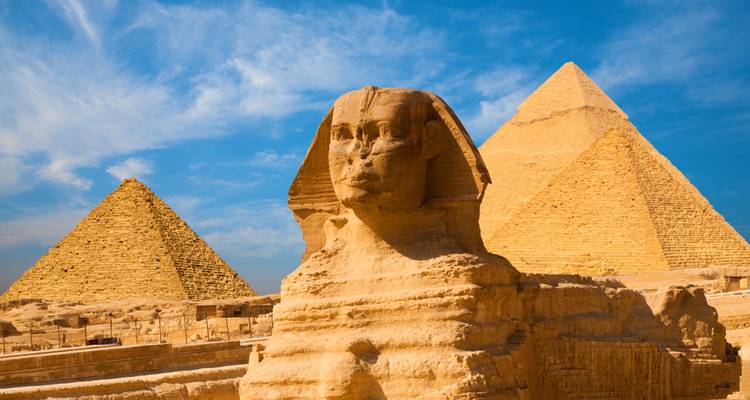 Le Grand Sphinx majestueux encadré par des pyramides imposantes sous un ciel bleu éclatant.
