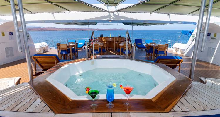 Deck einer Yacht mit Whirlpool und Getränken an einem sonnigen Tag.